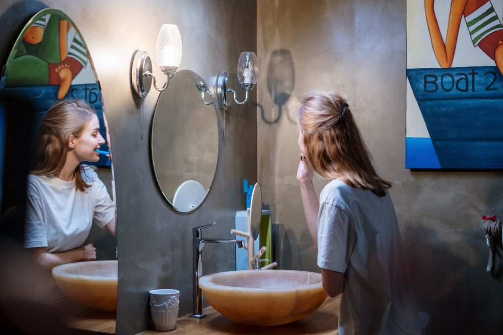 female brushing teeth in mirror image